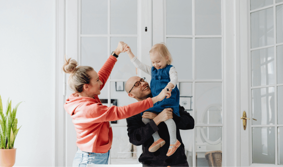A joyful family dancing together inside a bright Central Florida home, celebrating their home loan journey.