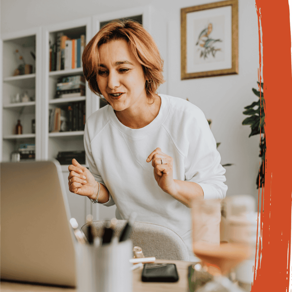 A woman smiling and celebrating in front of a laptop while reviewing her Orlando home refinancing options.
