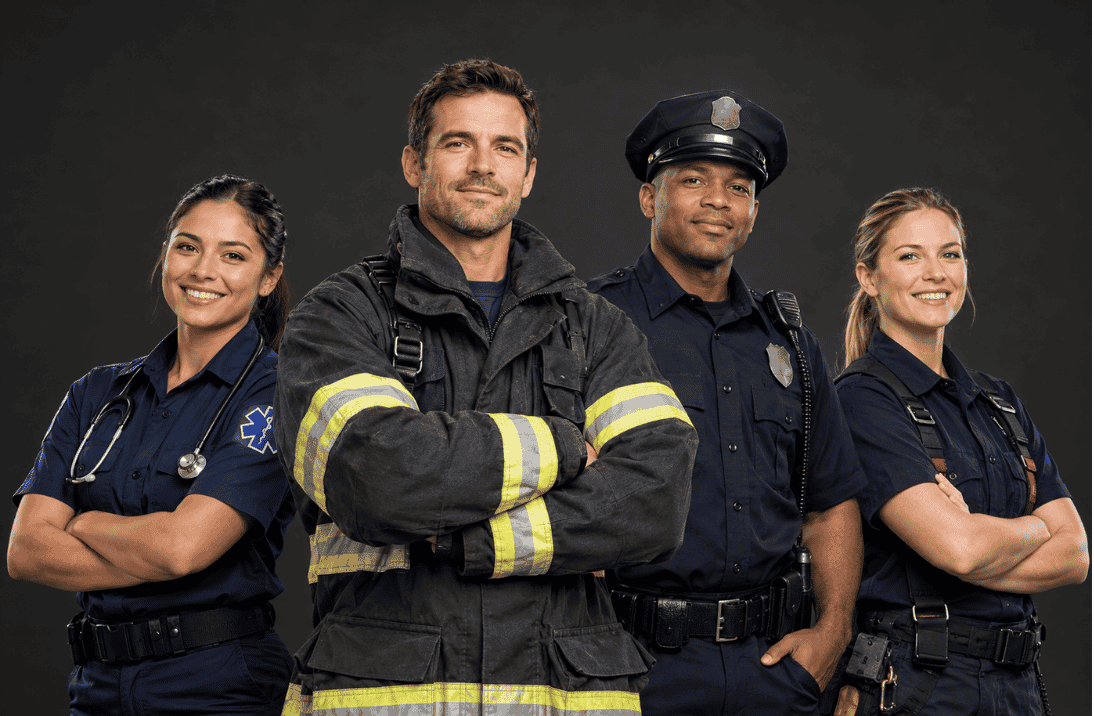 Four smiling first responders in uniform with arms crossed: a paramedic with a stethoscope, a firefighter, a police officer and a woman in a navy uniform, against a dark background