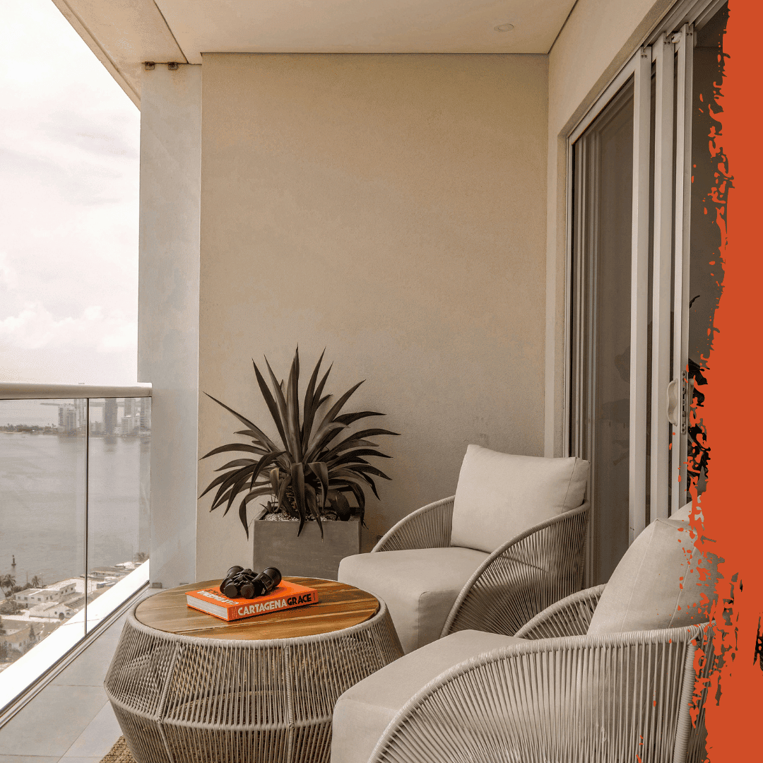 High-rise condo balcony with two woven chairs, a round table and a potted plant overlooking the water